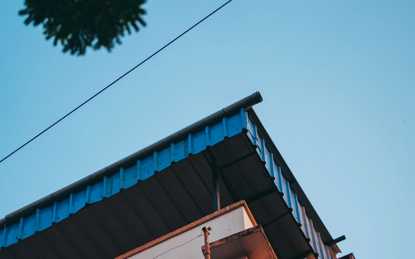 Residential building with a blue metal roof and deep roof overhang.