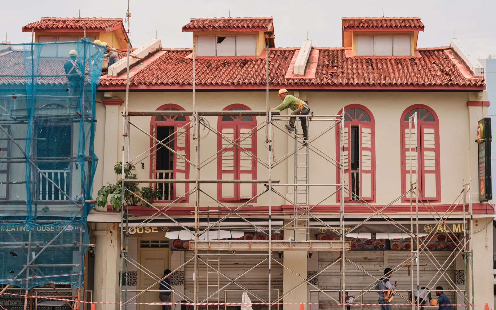 Workers using scaffolding during renovation of a historic building with a tile roof.