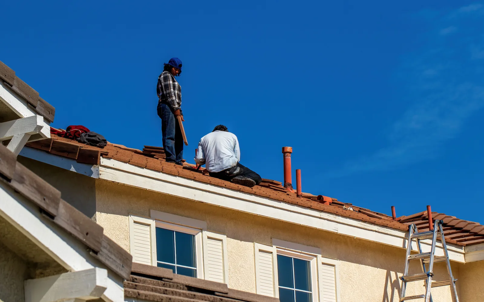 Workers repairing a roof deck after removal of the existing roof covering.
