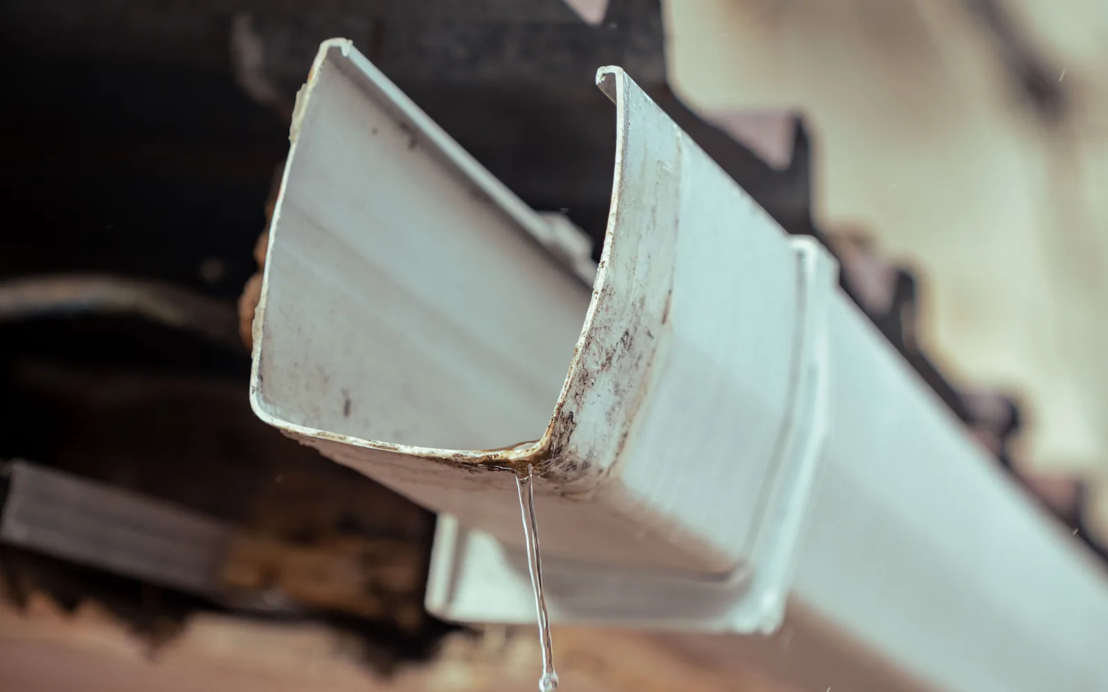 Close view of rainwater dripping from a roof gutter during wet weather.