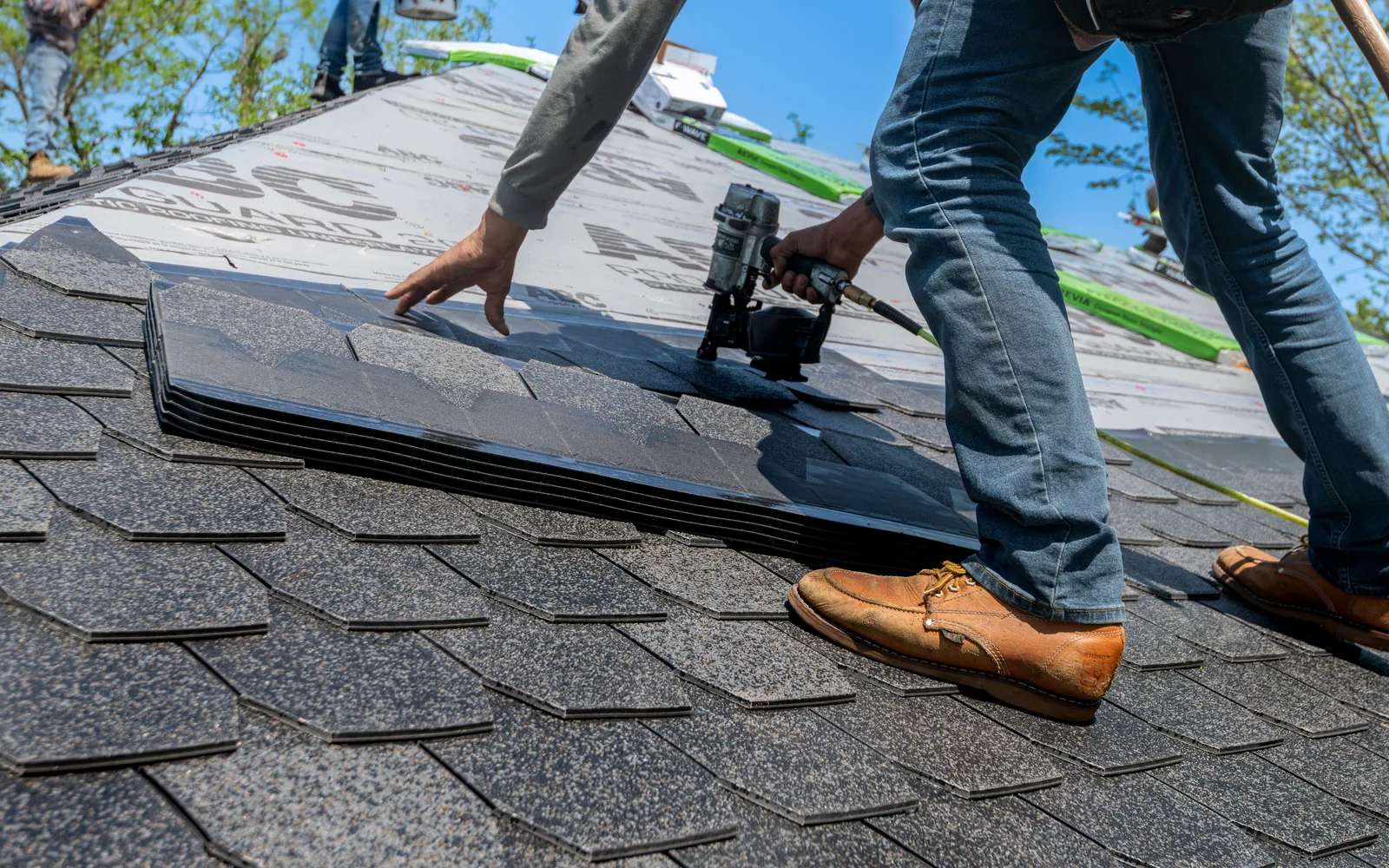 Close view of layered architectural asphalt shingles during installation.